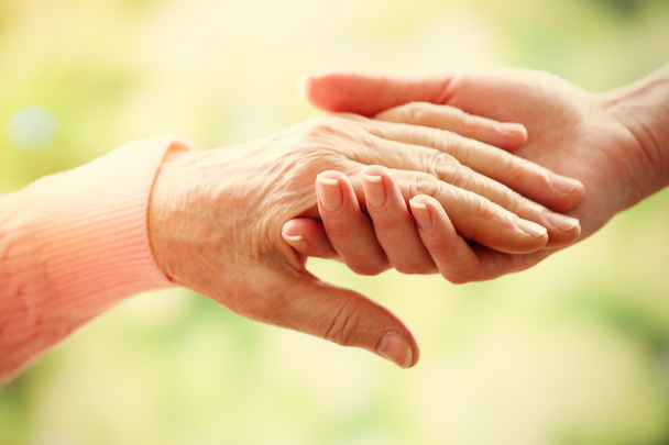 Old and young holding hands on light background, closeup - Foto, immagini
