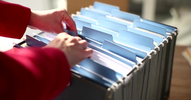 Donna cerca file in scatola indice carta in archivio aziendale. Gli impiegati controllano i documenti per trovare un contratto. Sistema organizzato di pratiche burocratiche in azienda - Filmati, video