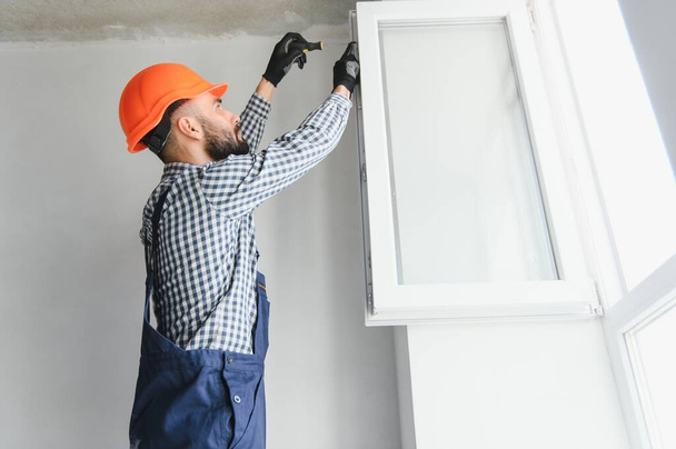 Worker in installing white plastic upvc window on house - Foto, Bild
