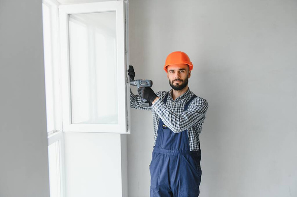 service man installing window with screwdriver. - Photo, image