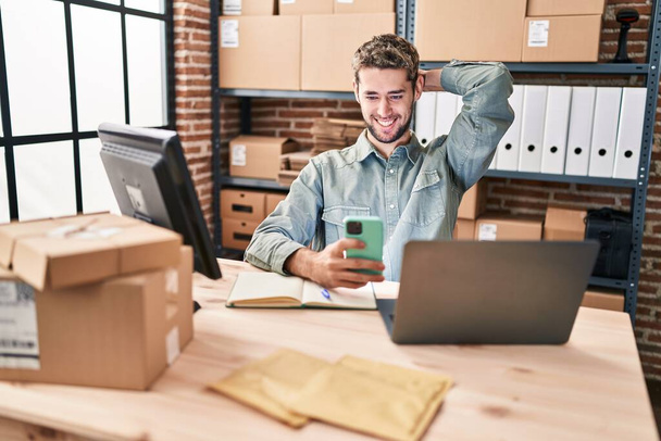 Молодой человек электронной коммерции бизнес-работник с помощью ноутбука и смартфона в офисе - Фото, изображение