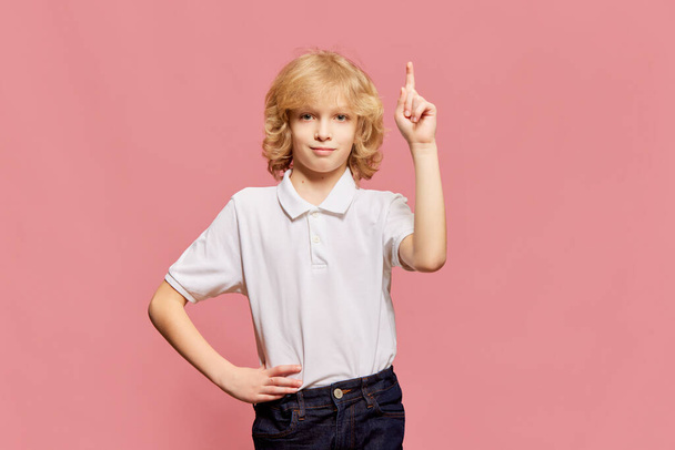 Smart, clever kid. Little boy, child posing in white shirt, rising finger up against pink studio background. Ideas. Motivated to study. Concept of childhood, emotions, facial expression. Ad - Foto, imagen