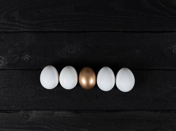 Huevos blancos y dorados en línea. Concepto Pascua - Foto, imagen