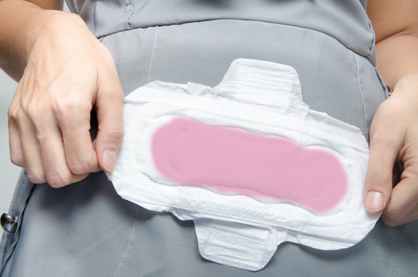 woman's hands holding a sanitary pad on green background close-u - Photo, Image
