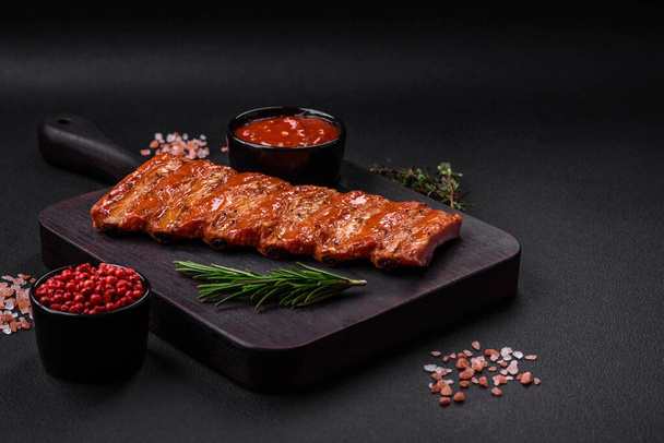 Delicious fresh grilled or smoked ribs with salt, spices and herbs on dark concrete background - Φωτογραφία, εικόνα