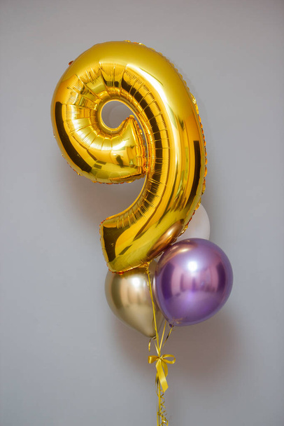gouden nummer 9 op een witte achtergrond en ballonnen - Foto, afbeelding