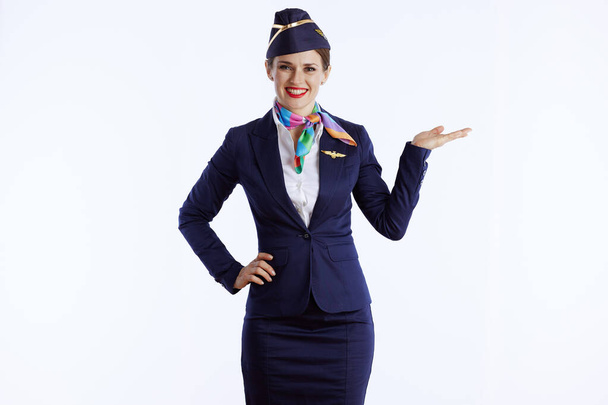 happy modern female air hostess isolated on white background in uniform presenting something on empty palm. - Foto, Imagen