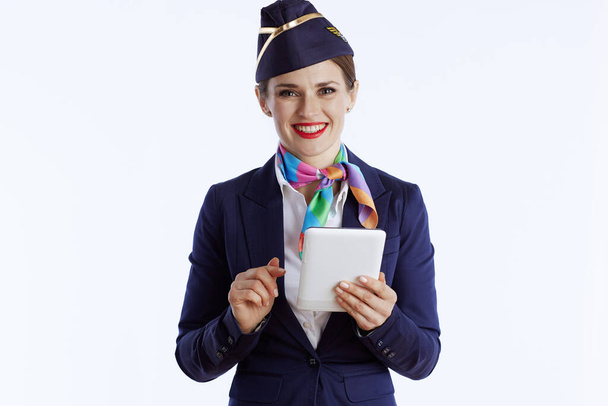 happy modern air hostess woman against white background in uniform using tablet PC. - Foto, afbeelding
