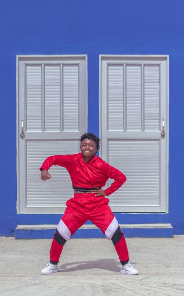 Jover mujer afro realiza baile estilo urban en parque local con pared azul y puertas de fondo - Photo, image