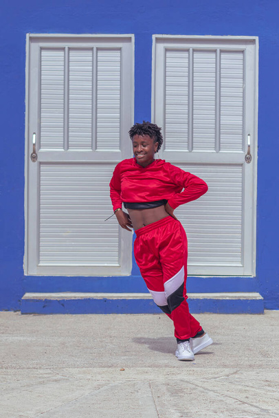 Jover mujer afro realizar baile estilo urbano en parque local con pared azul y puertas de fondo - Foto, imagen