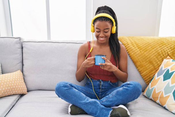 Afroamerikanerin hört zu Hause Musik und trinkt Kaffee - Foto, Bild