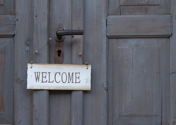 Panneau de bienvenue accroché à une vieille porte en bois
 - Photo, image