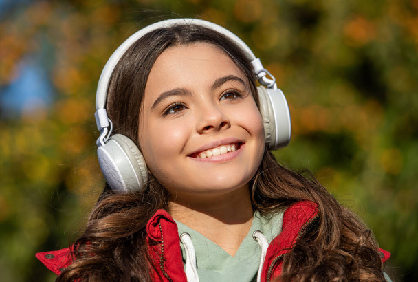 zdjęcie twarzy nastolatki słuchającej muzyki. nastolatka słucha muzyki na świeżym powietrzu. Nastolatka słuchająca muzyki na zewnątrz. nastolatka dziewczyna słuchanie muzyka noszenie słuchawki. - Zdjęcie, obraz