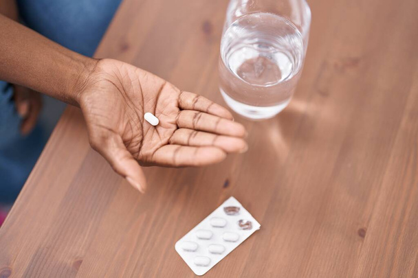 African american woman holding pill at home - Foto, Bild
