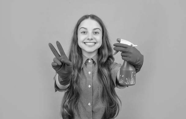 smiling kid in rubber gloves with spray bottle on blue background. peace. - 写真・画像