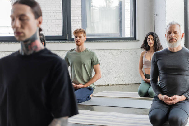 Interracial group of people meditating in Thunderbolt asana in yoga class  - Foto, afbeelding