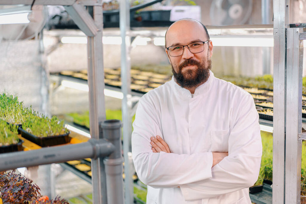 portrait of smiling male gardener in glasses and white coat microgreen farm Healthy vegan food Organic plant germination - Foto, Imagem