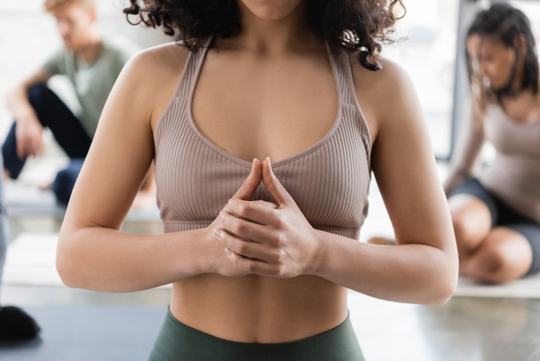 Cropped view of woman meditating near blurred people in yoga class  - Foto, immagini
