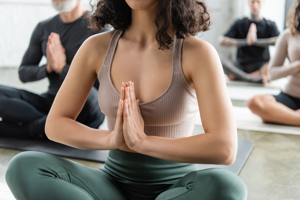 Vista recortada de la mujer en ropa deportiva meditando en clase de yoga borrosa  - Foto, Imagen