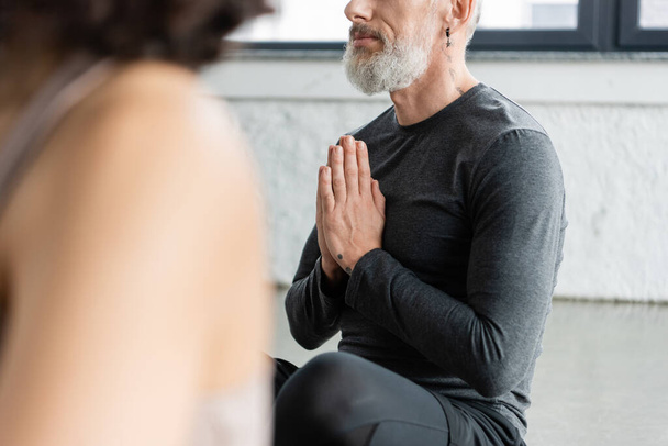 Cropped view of middle aged man practicing anjali mudra in yoga class  - Fotó, kép