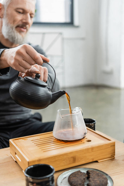 wazig volwassen man gieten thee uit pot in yoga klasse  - Foto, afbeelding