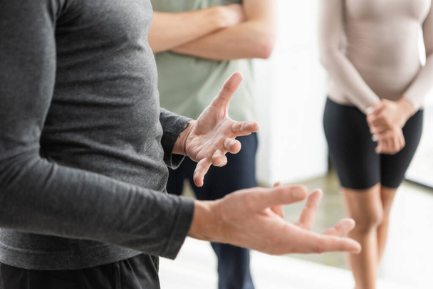 Cropped view of mature coach gesturing near blurred group in yoga class  - Fotografie, Obrázek