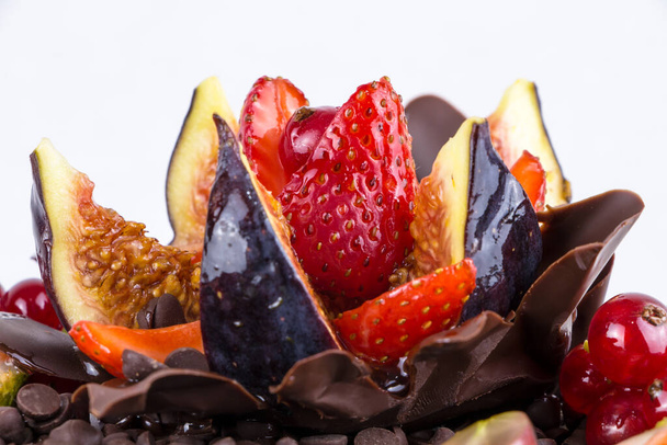 taart decoratie close-up, versierd met verse bessen, aardbeien, vijgen, druiven, beek en chocolade, geïsoleerd op witte achtergrond - Foto, afbeelding