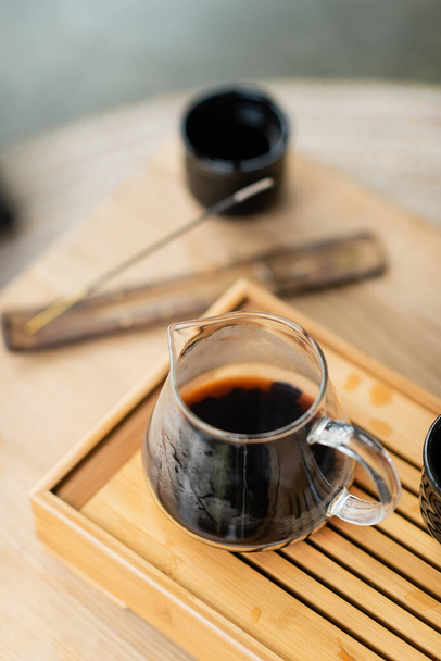 high angle view of focused brewed puer tea in glass jug on wooden stand - Photo, image