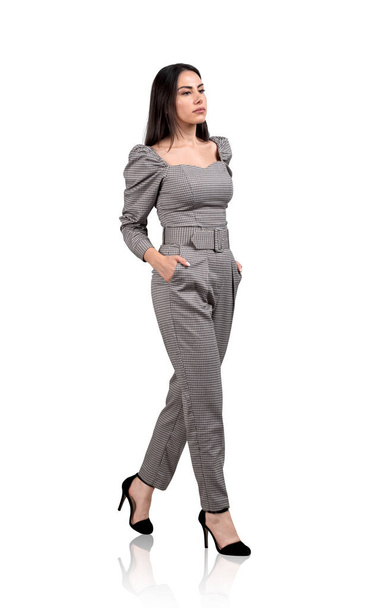 Businesswoman in jumpsuit walking hands in pocket, pensive look, isolated over white background. Concept of career development and management - Photo, image