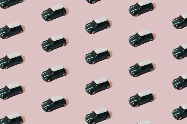 A small metallic green and white color car on a pink background. Pattern. - Photo, image