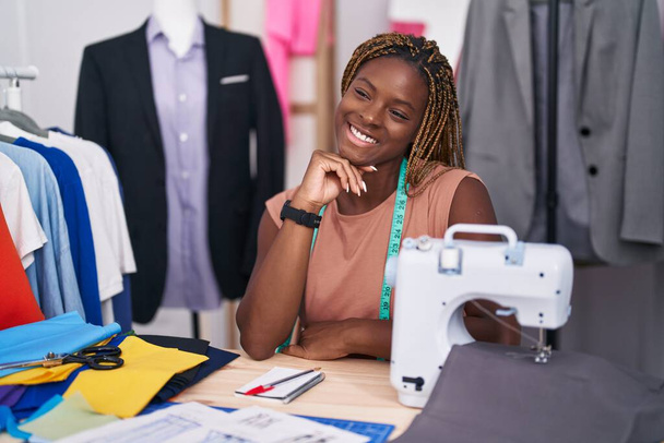 Afrikkalainen amerikkalainen nainen räätälöidä hymyillen luottavainen istuu pöydällä räätäli shop - Valokuva, kuva
