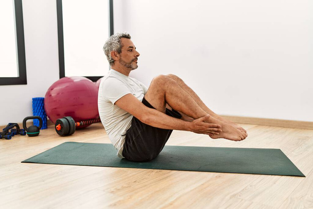 Středního věku šedovlasý muž trénink abs cvičení ve sportovním centru - Fotografie, Obrázek