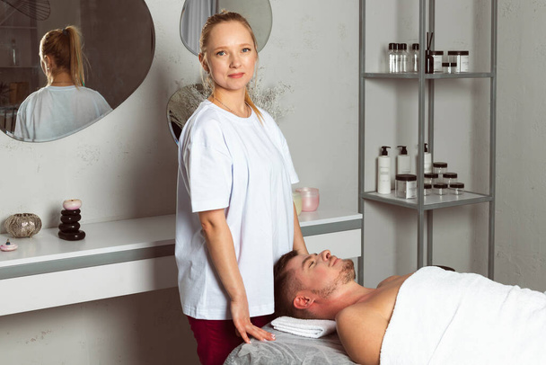 Portrait of the professional masseuse or massage therapist standing next to a happy satisfied client. - Fotografie, Obrázek