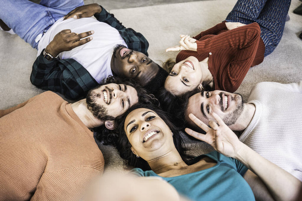 Kampüsün oturma odasında uzanan çok ırklı gençler mutlu çok kültürlü arkadaşlar selfie çekiyorlar ve kameraya gülümsüyorlar. - Fotoğraf, Görsel