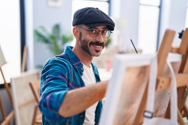 Молодий іспаномовний художник посміхається впевнено малює в художній студії
 - Фото, зображення