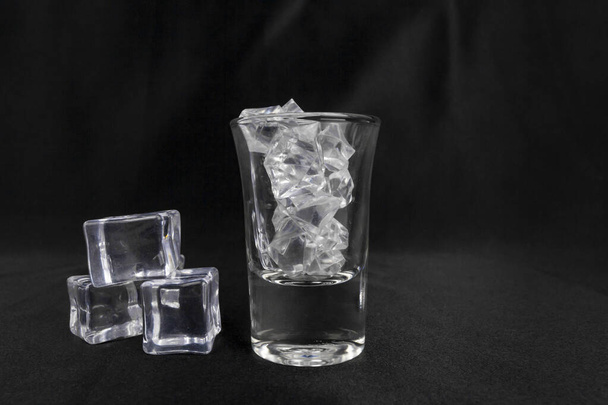 Um tiro de vidro com gelo isolado em preto. - Foto, Imagem