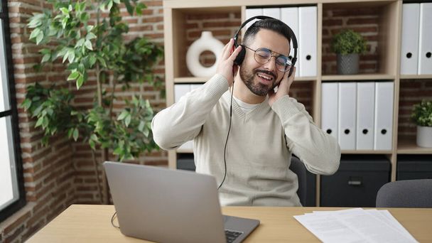 Giovane uomo ispanico operaio ascoltando musica ballare in ufficio - Foto, immagini