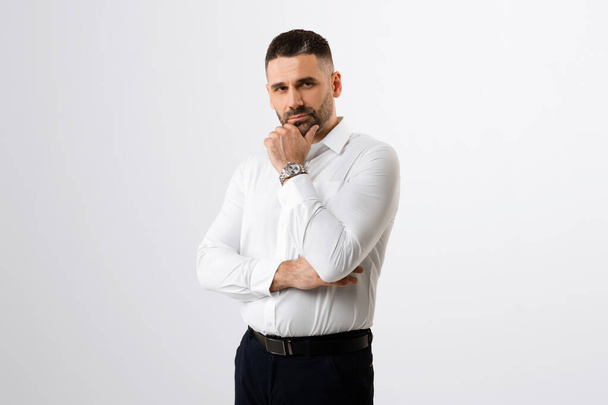 Pensive businessman touching chin and looking at camera, male entrepreneur thinking about business offer or new startup while standing on grey background - Fotó, kép