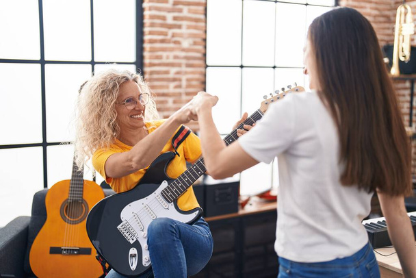 Two women musicians bump fists at music studio - Foto, Bild