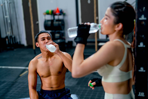 Asian sport man and woman drink water from bottle after finish of training in fitness gymm. - Φωτογραφία, εικόνα