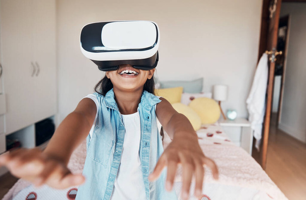 Τα παιχνίδια έγιναν πιο τεχνικά. ένα νεαρό κορίτσι που χρησιμοποιεί ακουστικά εικονικής πραγματικότητας στο σπίτι - Φωτογραφία, εικόνα