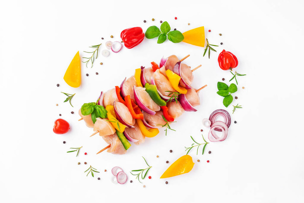 Skewers with pieces of raw meat,red,yellow,green pepper.Top view.Raw chicken skewers with vegetables,peppers,onions,on a white background.Chicken Skewers breast fillet meat.Uncooked mixed meat skewer. - Foto, Imagem