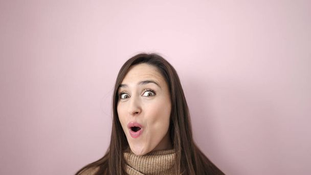 Beautiful hispanic woman standing with surprise expression over isolated pink background - Fotó, kép