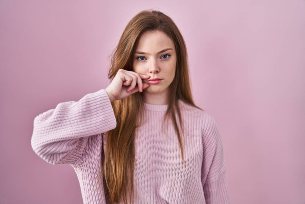 Young caucasian woman standing over pink background mouth and lips shut as zip with fingers. secret and silent, taboo talking  - Photo, image