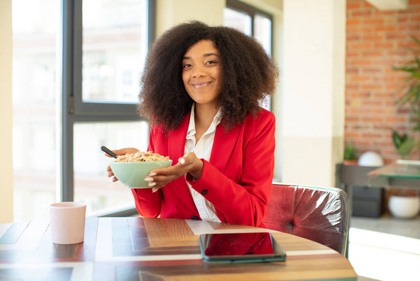 pretty afro black woman smiling cheerfully, feeling happy and showing a concept. having breakfast concept - Foto, immagini