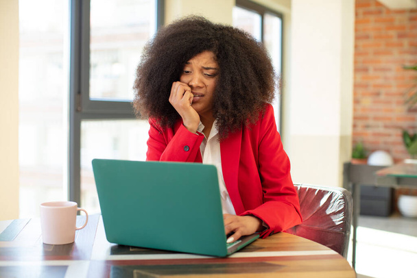 pretty afro black woman feeling scared, worried or angry and looking to the side. businesswoman and laptop concept - Photo, image