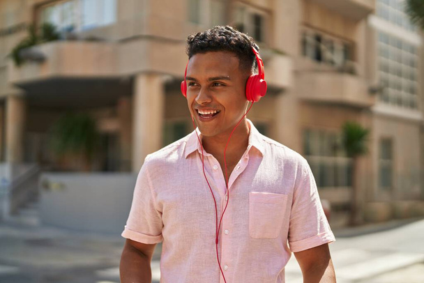 Young latin man smiling confident listening to music at street - Zdjęcie, obraz