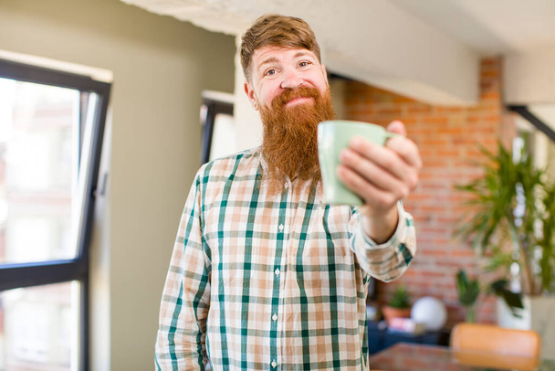 red hair man red hair man smiling cheerfully, feeling happy and pointing to the side with a coffee mug - Fotoğraf, Görsel
