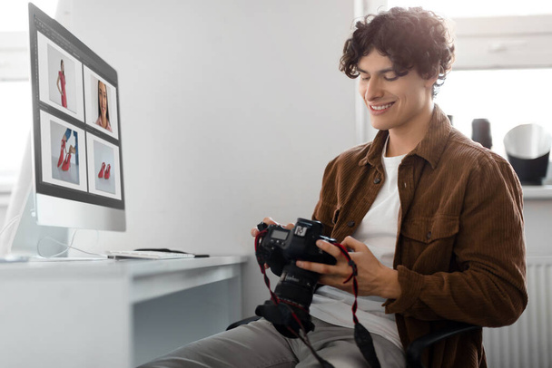 Fotograf prohlíží fotografie na své DSLR kameře, sedí u stolu s počítačem, muž pracující s post-procesorem editační software na moderní ploše - Fotografie, Obrázek