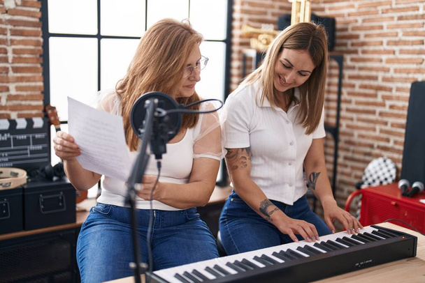Mother and daughter musicians singing song playing piano at music studio - Valokuva, kuva